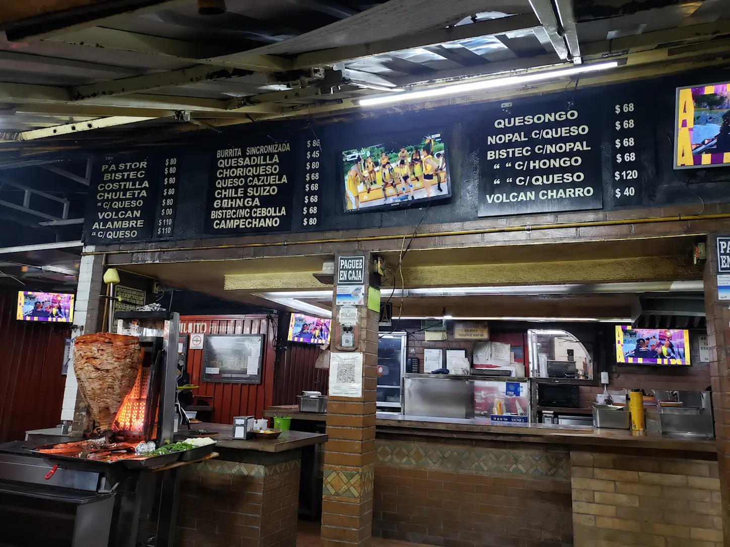 El Vilsito Mexico City al pastor taqueria with trompo, counter seating, and menu boards