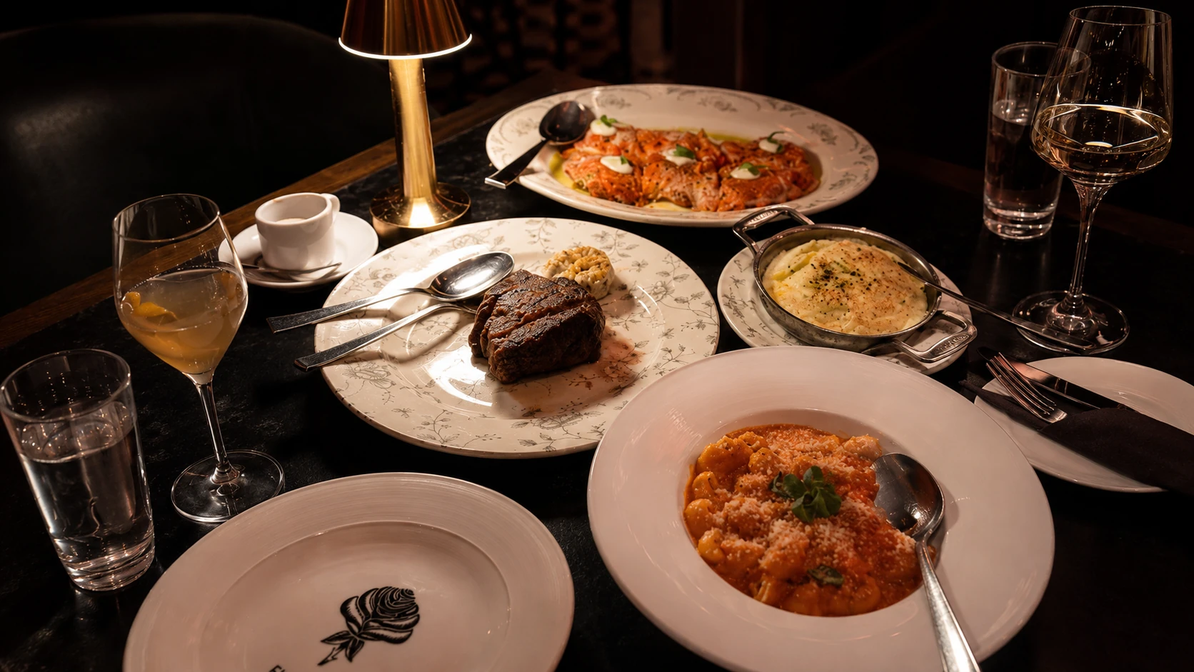 Pasta, steak, wine, and sides on a dinner table at Fioretta Chicago