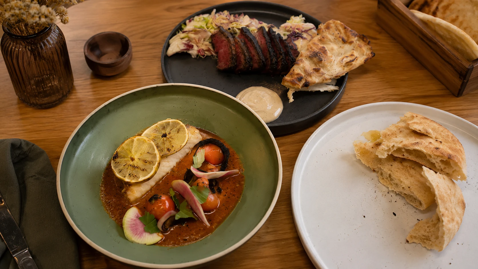 Shared Middle Eastern dishes with fish, steak, and pita at Galit Chicago