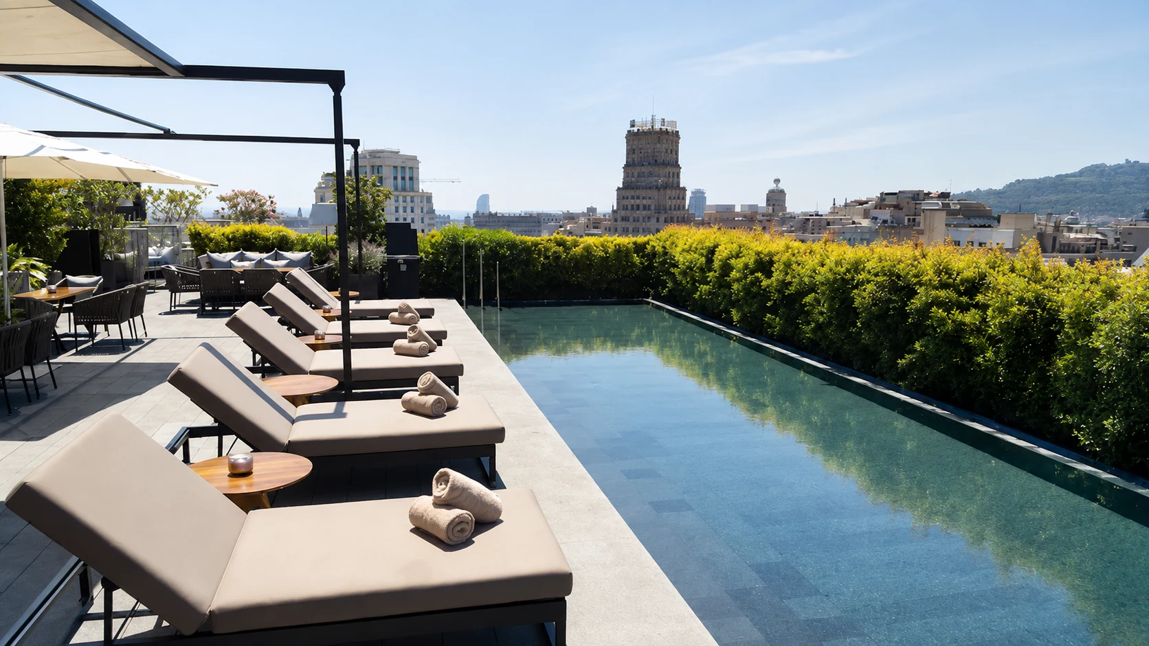 Mandarin Oriental Barcelona rooftop pool with lounge chairs, greenery, and city views