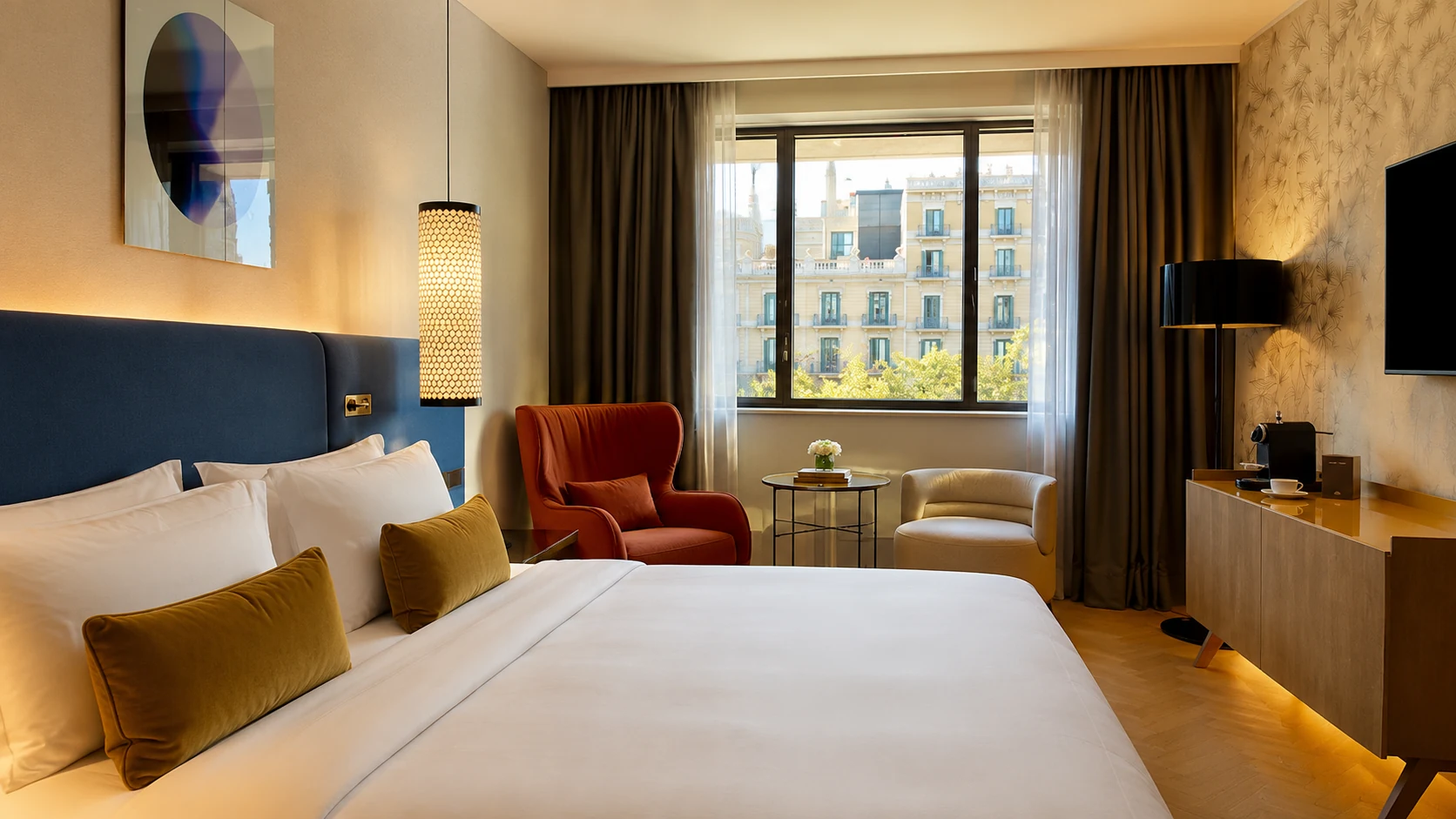 Mandarin Oriental Barcelona guest room with blue headboard, warm lighting, and city view