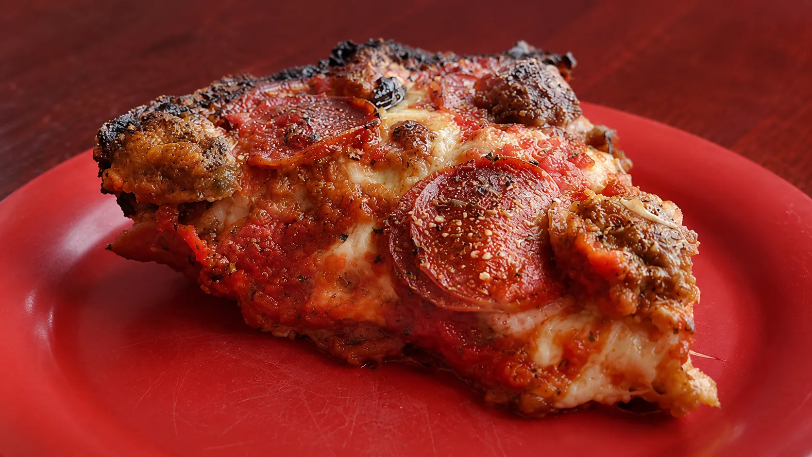 Slice of caramelized crust pan pizza at Pequod’s Pizza in Chicago