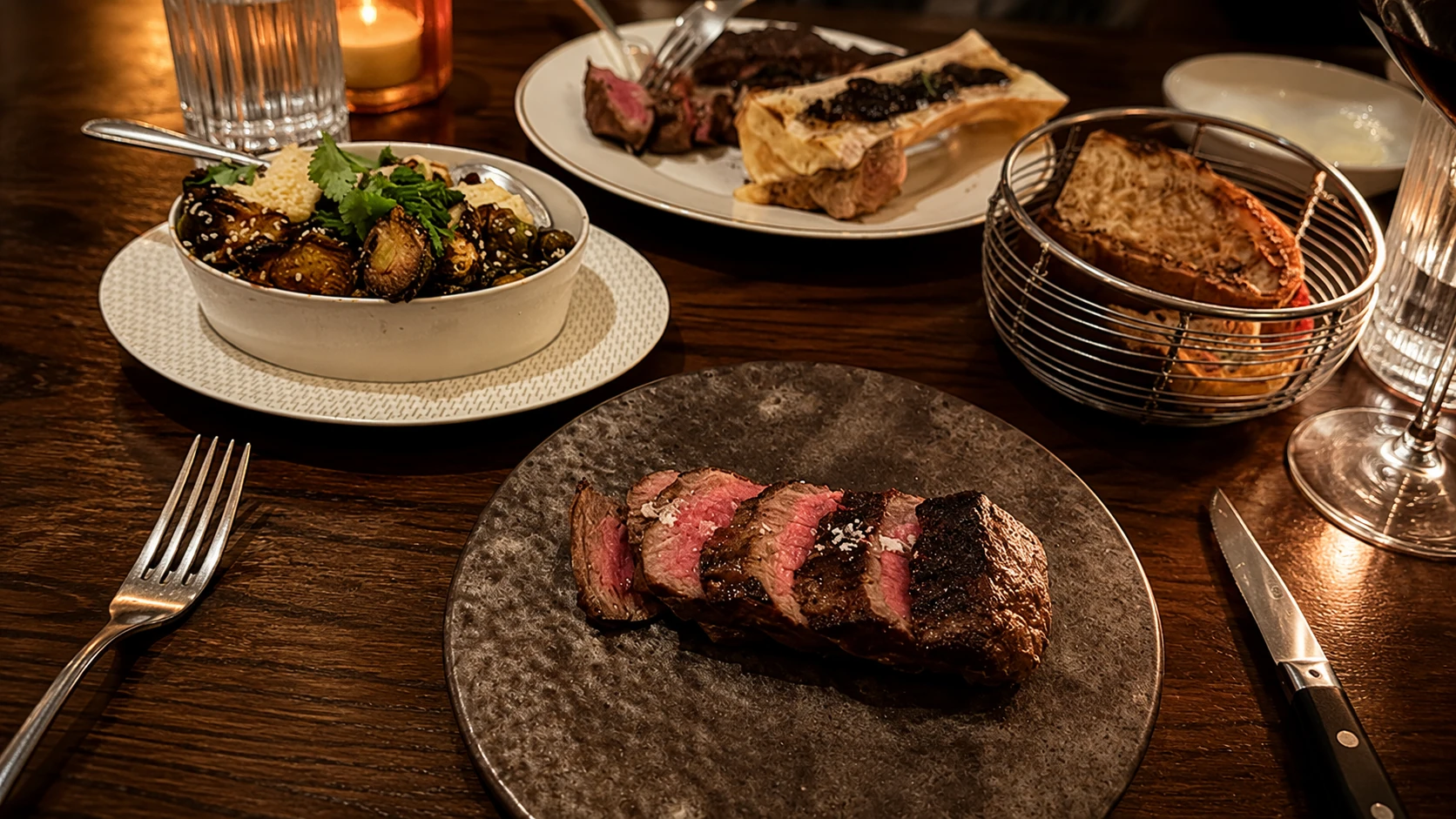 Steak and sides on a dark wood table at Swift and Sons in Chicago
